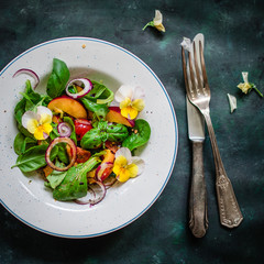 Coloful summer salad with nectarines and edible flowers. Top view.