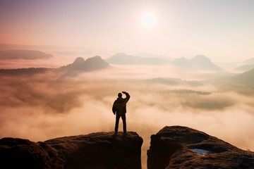 Man stands on peak of sandstone rock in national park 