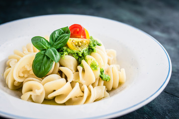 Noodles with vegan pesto and colorful tomatoes. Selective focus.