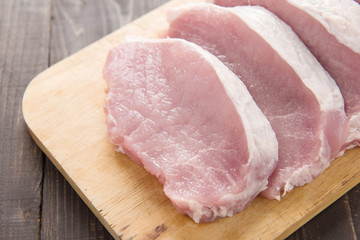 Raw pork on cutting board on wooden background.