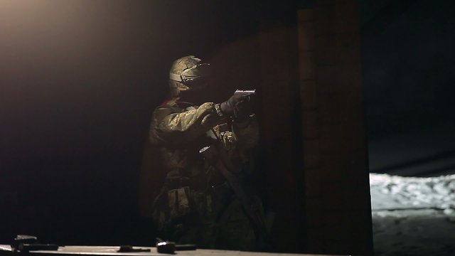 The soldier fires his gun at night