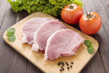 Raw pork on cutting board and vegetables