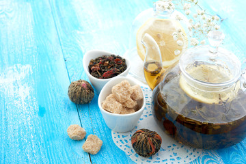 Ripe lemon, cinnamon and fruit drink in glass teapot on wooden