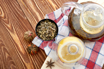 Ripe lemon, cinnamon and fruit drink in glass teapot on wooden