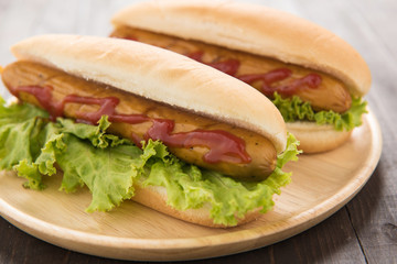 Hot dog with ketchup on wooden background.