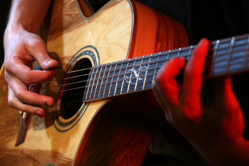 Fototapeta premium Young man playing on acoustic guitar close up