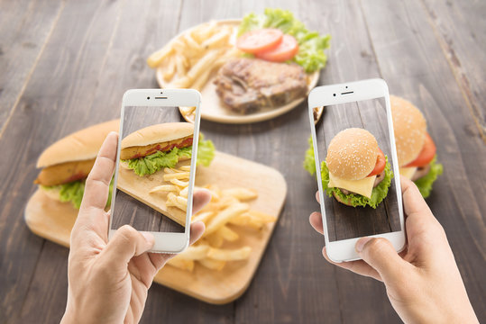 Friends using smartphones to take photos of hot dog and hamburge