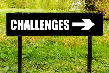 CHALLENGES written on directional black metal sign