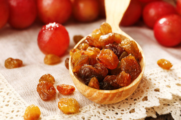 Raisins in wooden spoon with grapes on table close up