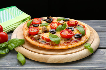 Tasty pizza with vegetables and basil on black background