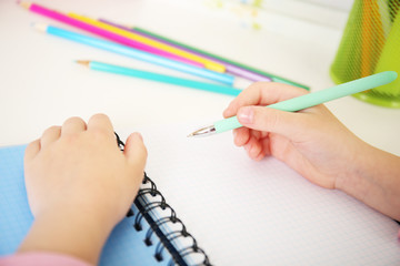 Kids hands drawing on notebook at desktop, closeup