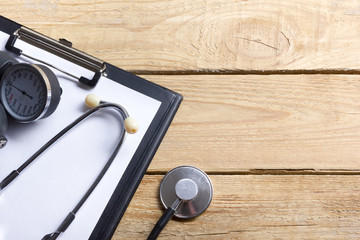 Workplace of a doctor. Blank Medical clipboard and stethoscope on wooden desk background. Top view