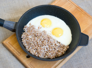 Buckwheat porridge with two fried eggs on a pan 