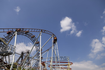 An amusement park with some rides on a blue sky with clouds