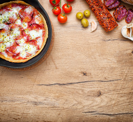 Top view of pizza in iron pan with ingredients. Place for your text.