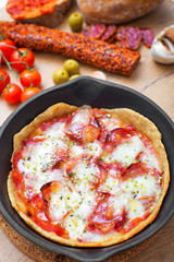 Top view of pizza in iron pan with ingredients.