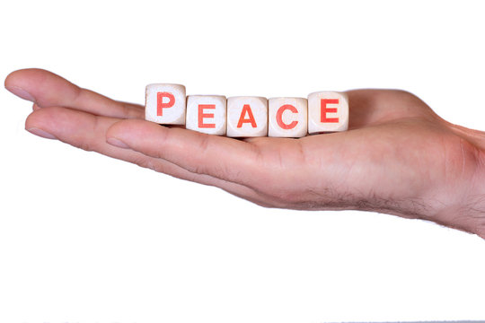 Peace written with wooden dice on a isolated hand