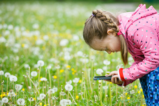 Little girl exploring nature with her smartphone