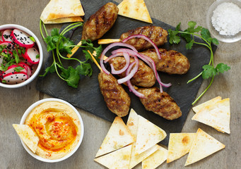 Kyufta (barbecue) of lamb with snacks (radish salad, chips and hummus.)