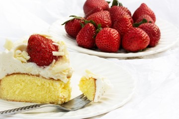 Slice of strawberry cream cake close up on white background, selective focus