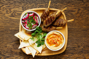 Kyufta (barbecue) of lamb with snacks (radish salad, chips and hummus.)