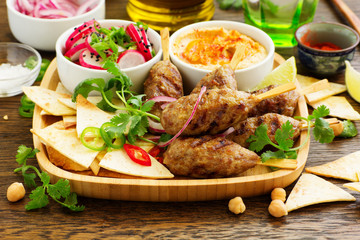 Kyufta (barbecue) of lamb with snacks (radish salad, chips and hummus.)