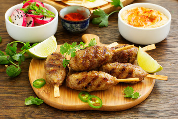 Kyufta (barbecue) of lamb with snacks (radish salad, chips and hummus.)