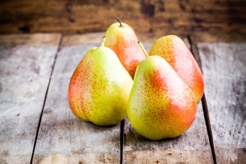Four fresh organic ripe pears on rustic background