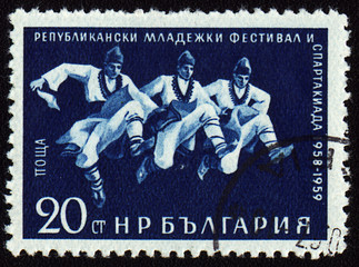 Three dancing men in Bulgarian national costumes on post stamp