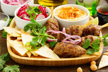 Kyufta (barbecue) of lamb with snacks (radish salad, chips and hummus.)