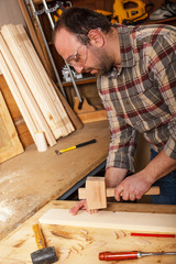 Carpenter hammering wood dowel in a piece of wood