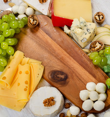 various types of cheese  on a wooden board .