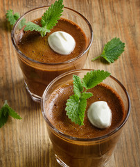 Homemade Chocolate Mousse in glasses on a rustic wooden table.