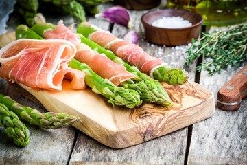 Fresh organic asparagus with prosciutto on a cutting board