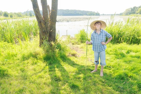 Smiling angling teenage boy with handmade green twig fishing rod in hand