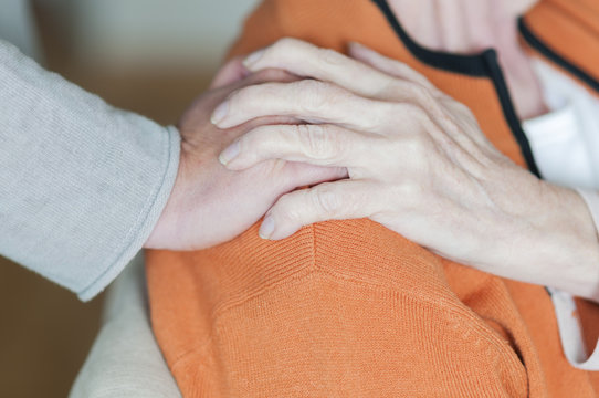 Frau haelt Hand auf der Schulter einer Seniorin