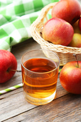Glass of apple juice with apples on grey wooden background