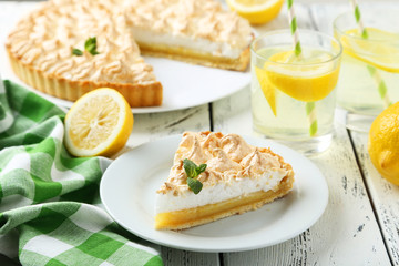 Lemon meringue pie on plate on white wooden background