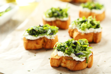 Tasty fresh bruschetta on parchment on grey wooden background