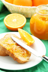 Bread with orange jam on green background