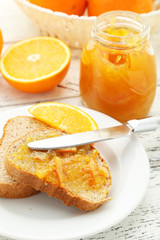 Fototapeta na wymiar Bread with orange jam on white wooden background