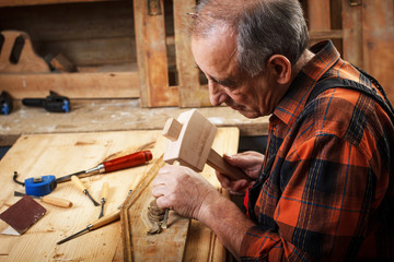 Senior carpenter restoring old furniture in his workshop