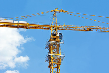 Yellow construction tower crane against blue sky