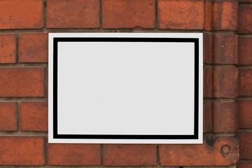 Weisses Schild mit schwarzem Rand auf roter Ziegelsteinwand