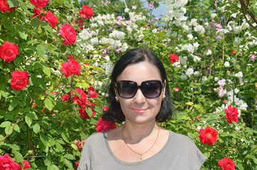 Красивая женщина, брюнетка, в кустах цветов розы и жасмина