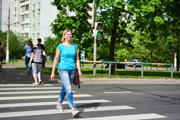 Young woman crossing road at green light