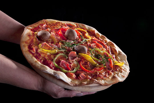 Pizza auf Händen im dunklen Licht
