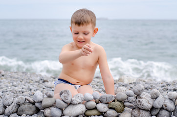 Young Boy Building Stone Wall on Rocky Beach