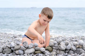 Young Boy Building Stone Wall on Rocky Beach