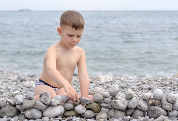 Young Boy Building Stone Wall on Rocky Beach